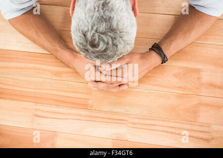 Überarbeitete lässige Geschäftsmann stützte sich auf Schreibtisch aus Holz Stockfoto