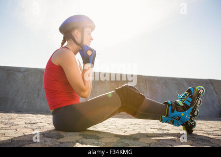 Sportliche blonde Skater am Boden sitzen und Befestigung Helm Stockfoto