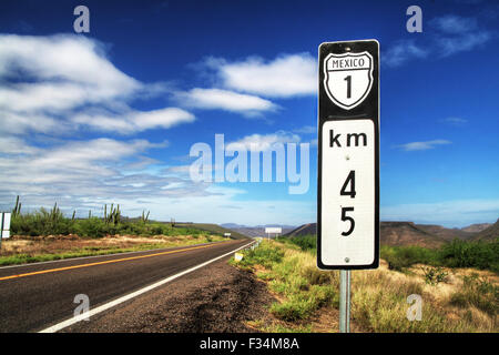 Mexiko 1 Schild auf einsamer Straße über wilde Natur unter einem blauen Himmel mit einigen weissen Wolken, Baja California, Mexiko Stockfoto