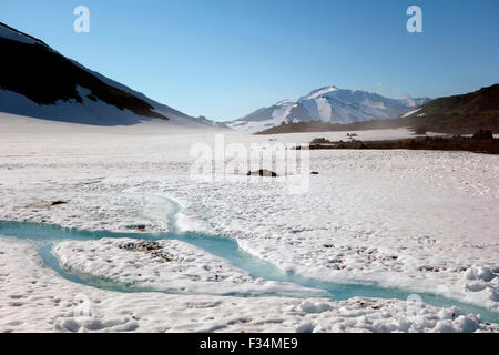 Strom unter dem Schnee und Ansicht des Vulkans Mutnowski in der Ferne, Kamtschatka, Russland Stockfoto