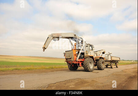 Großer Traktor fährt auf Landstraße. Stockfoto