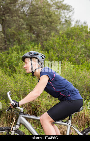 Lächelnde athletische Blondine Mountainbiken Stockfoto