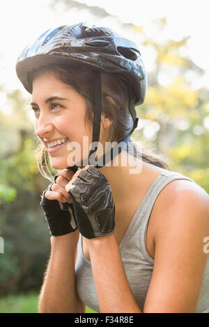 Lächelnd, sportliche Brünette aufsetzen Helm Stockfoto