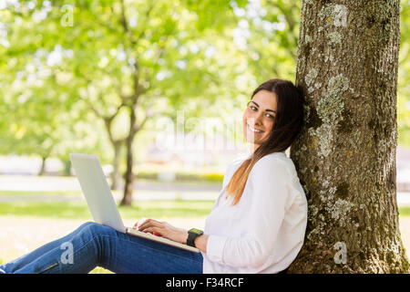 Schöne Brünette mit Laptop im park Stockfoto