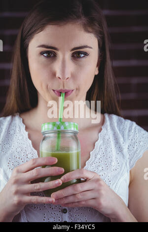 Hübsche Frau, nippen an grüner Saft Stockfoto