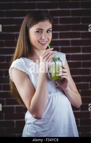 Hübsche Frau, nippen an grüner Saft Stockfoto