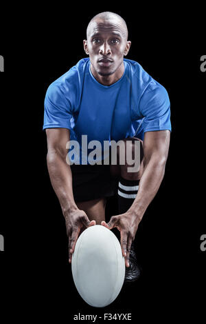 Porträt des Rugby-Spieler mit Ball kniend Stockfoto