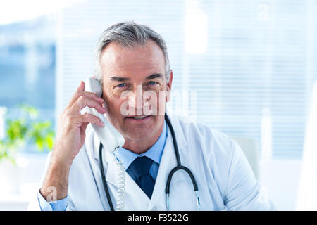 Männlichen Arzt Gespräch am Telefon in Klinik Stockfoto
