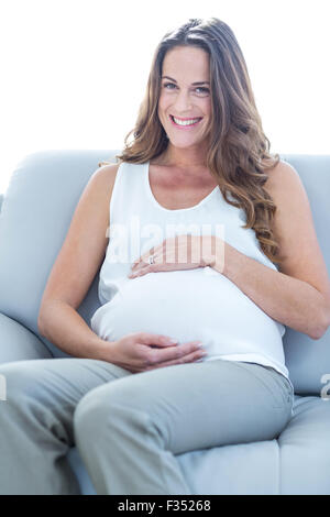 Glücklich schwanger Frau sitzend auf sofa Stockfoto