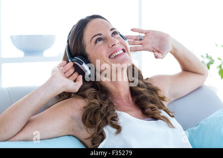 Lächelnde Frau Musik hören zu Hause Stockfoto