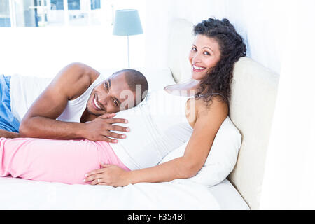 Porträt des Menschen hören auf Bauch der schwangeren Frau auf Bett Stockfoto