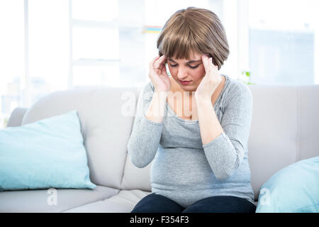 Schwangere Frau, die Kopfschmerzen auf couch Stockfoto