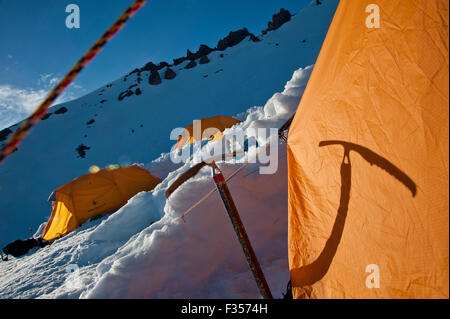 Abendsonne wirft den Schatten von einem Eispickel auf einem Zelt am Mount Shasta, Shasta Trinity National Forest, California. Stockfoto