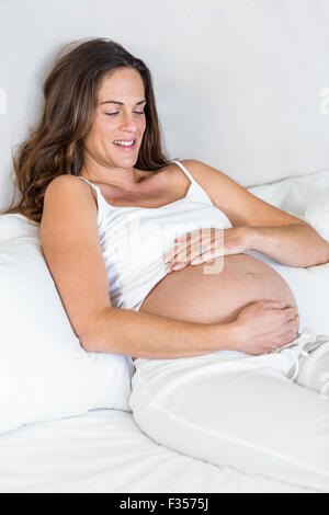 Glückliche Frau sitzt auf Bett Stockfoto