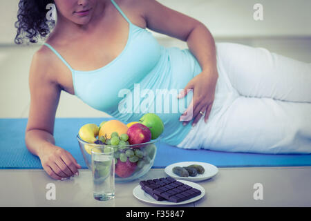 Schwangere Frau liegend von Früchten und Schokolade Stockfoto