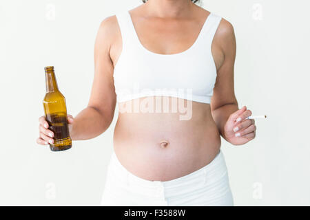 Schwangere Frau mit Zigarette und Bier Flasche Stockfoto