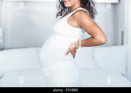 Schwangere Frau hält sie zurück beim stehen im Schlafzimmer Stockfoto