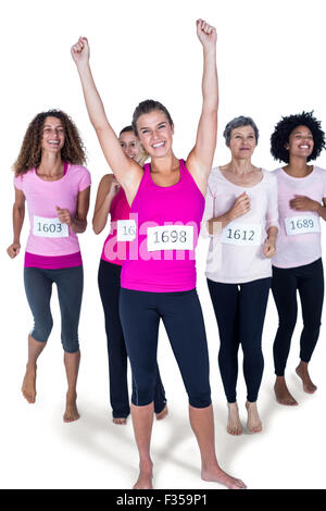 In voller Länge Portrait lächelnder Sieger Athlet mit erhobenen Armen und andere laufen Stockfoto