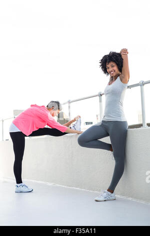 Glückliche junge Frau stretching mit Freundin Stockfoto