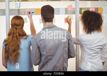 Rückansicht des Business-Leute, die Schreiben an Glaswand Stockfoto