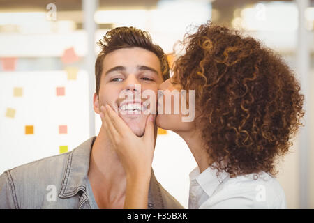Frau mit lockigem Haar küssen Geschäftsmann Stockfoto