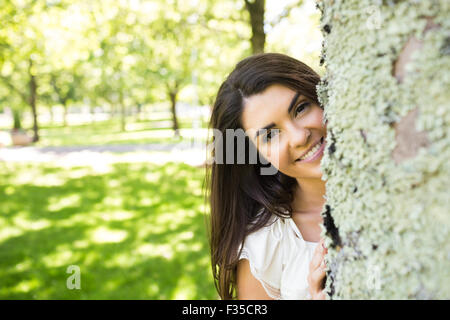 Porträt der jungen Frau hinter Baumstamm Stockfoto