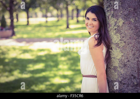 Porträt der stets gut gelaunte Frau stützte sich auf Baum Stockfoto