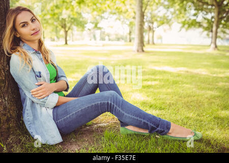 In voller Länge Portrait von glücklich Frau sitzt unter Baum Stockfoto