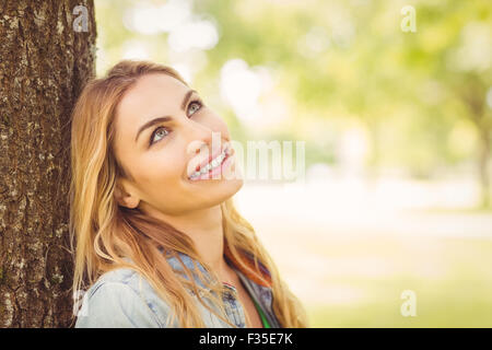 Lächelnde Frau blickte sitzend unter Baum Stockfoto