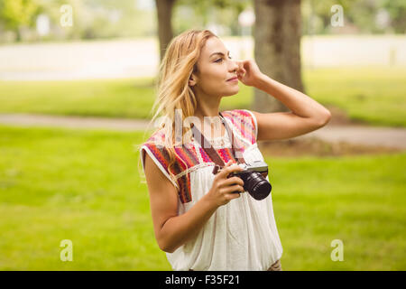 Lächelnde Frau Holding Digitalkamera im stehen auf dem Rasen Stockfoto