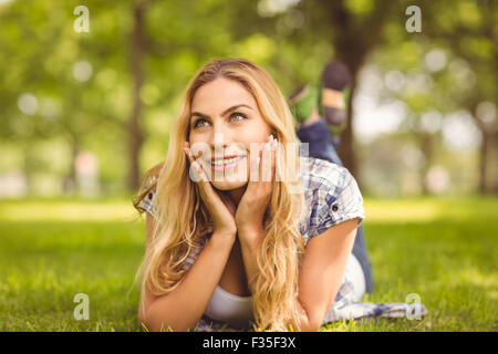 Lächelnde nachdenkliche Frau liegend auf Vorderseite Stockfoto