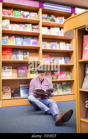 Mann liest Buch sitzend auf Etage Stockfoto