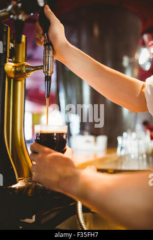 Barkeeper hält Glas unten Dispenser Zapfhahn Stockfoto