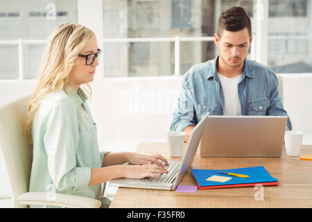 Ernsthafte Menschen, die Arbeiten am Laptop beim Sitzen am Schreibtisch Stockfoto