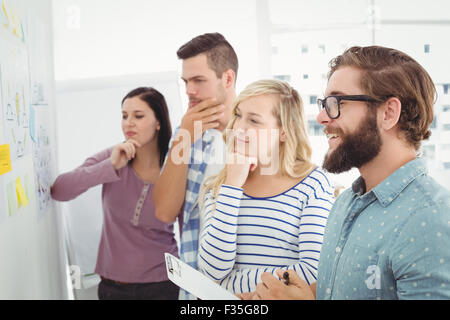 Nachdenklich Geschäftsleute auf Wand mit Notizen und Zeichnungen zeigen Stockfoto