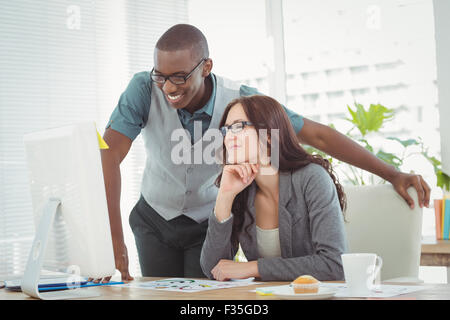 Lächelnde Geschäftsleute Blick auf Computer während der Arbeit am Schreibtisch Stockfoto