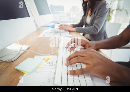 Hände, die Eingabe über die Tastatur am Computer-Schreibtisch mit Kollegen abgeschnitten Stockfoto