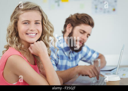 Porträt der lächelnde Frau mit Hand am Kinn und Mann arbeitet auf laptop Stockfoto