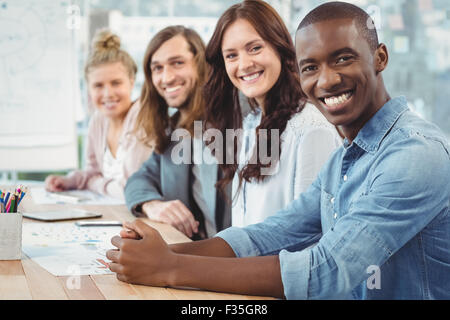 Porträt des Lächelns Geschäftsleute sitzen in Reihe am Schalter Stockfoto