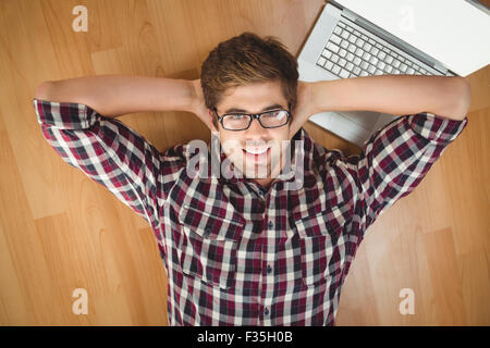 Geschäftsmann lächelnd liegend vom Laptop auf Parkett Stockfoto