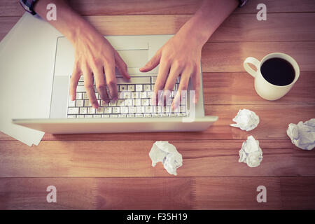Mann arbeitet auf Laptop von schwarzen Kaffee am Schreibtisch im Büro Stockfoto