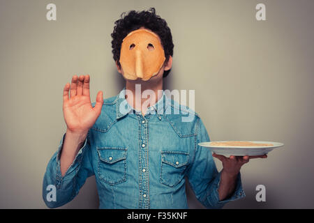 Junger Mann hat gebt in einen Pfannkuchen geschnitten und trägt es auf seinem Gesicht Stockfoto