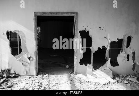 Verlassene Gebäudeinnenraum. Leere Tor und Löcher in der Wand. Schwarz / weiß Foto Stockfoto