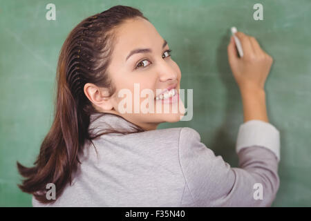 Rückansicht des hübschen Lehrerin an Tafel schreiben Stockfoto