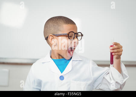 Überrascht Schüler mit Laborkittel Reagenzglas betrachten Stockfoto