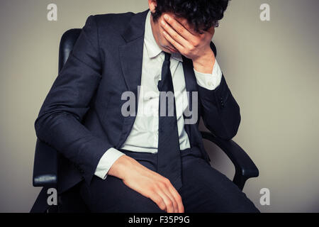 Traurig und müde Geschäftsmann sitzt in einem Bürostuhl Stockfoto