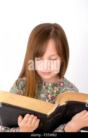 Kleines Kind, das Lesen der Bibel auf weißem Hintergrund Stockfoto