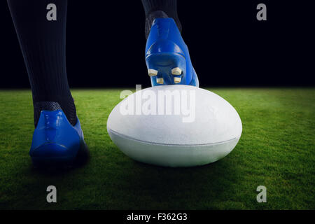 Zusammengesetztes Bild des Rugby-Spieler, die Füße auf den ball zu posieren Stockfoto