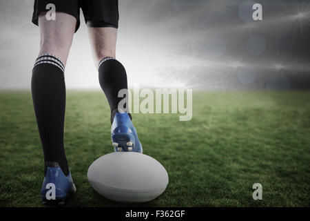 Zusammengesetztes Bild des Rugby-Spieler, die Füße auf den ball zu posieren Stockfoto