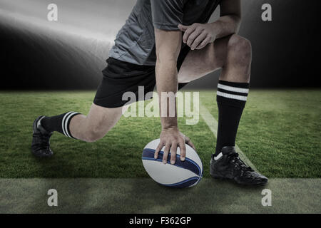 Zusammengesetztes Bild des Rugby-Spieler aus schwarzem Jersey stretching mit Kugel Stockfoto